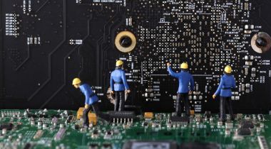 An image of miniature figures working on a computer’s motherboard to show the idea of working on a software engineering team. 