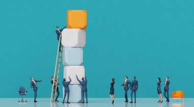 An image of miniature figures adding blocks to a stack and a ladder to show the idea of climbing the career ladder at work.