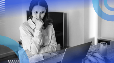 A young woman looks at a laptop with an expression of concern