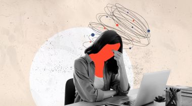 A person working on their laptop with a red face, as if they are experiencing frustration