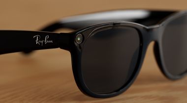 A pair of Meta Ray-Ban smart glasses rest on a wooden surface.
