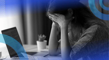 A young woman holds her head in her hands in a dejected manner in front of a laptop