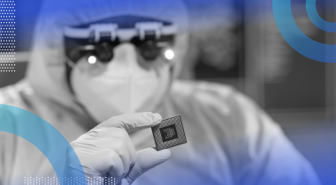 A researcher in a clean suit holds a semiconductor