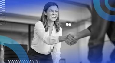 A woman smiles and shakes hands over a desk