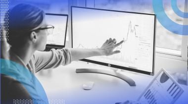 A financial analyst looks at dashboards on computer screens