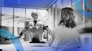A robot talks to a woman across a desk