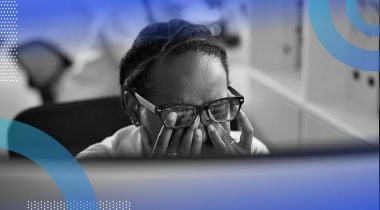 A developer rubs their eyes while looking at a computer screen