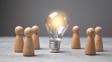 A photo of wooden figures around a lightbulb to show the idea of a great employee experience