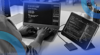 A developer works on code on a laptop and a tablet