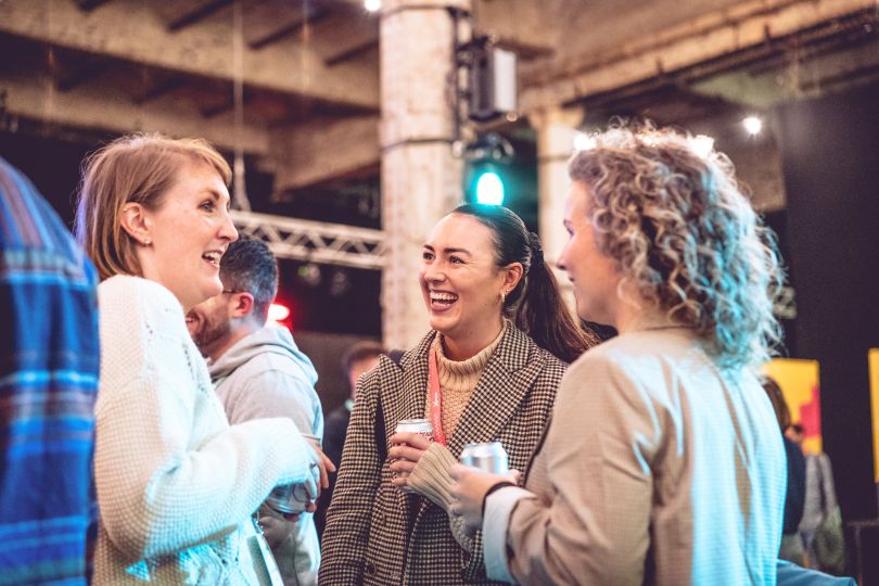 Three women in business attire standing in a circle and talking to each other.