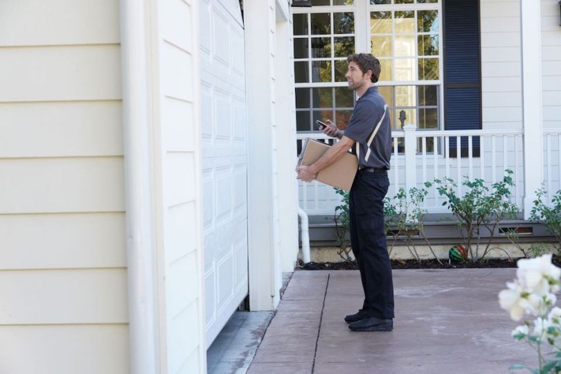 Amazon delivery man stands outside of home garage door