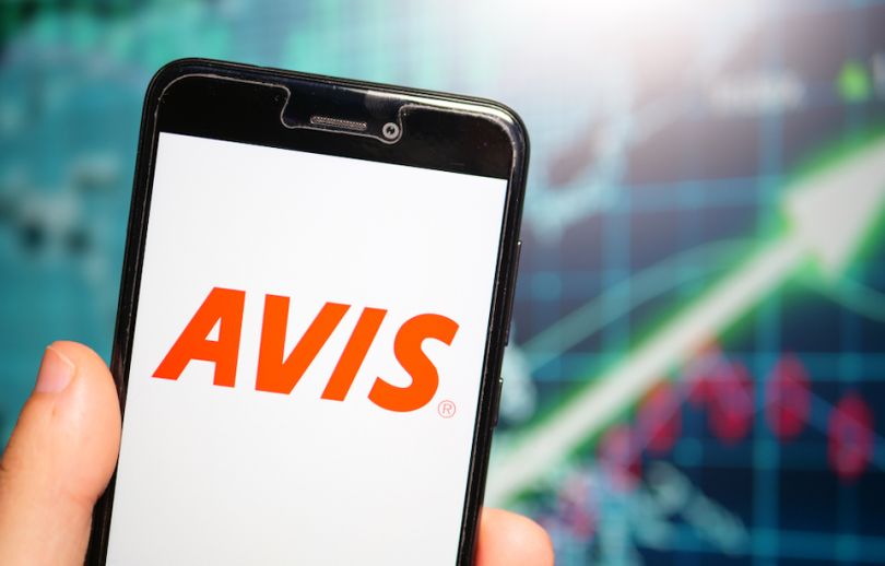 Hand holding a cellphone with Avis logo on screen