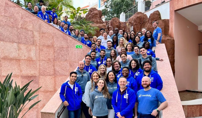 Candidly employees stand on a staircase