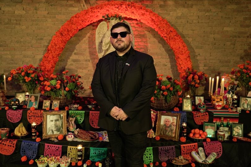 CASHDROP founder and CEO Ruben Flores-Martinez stands in front of a Día de Muertos alter