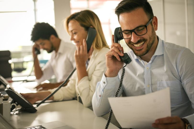 Stock image of three people using phones, potentially with DialogTech software