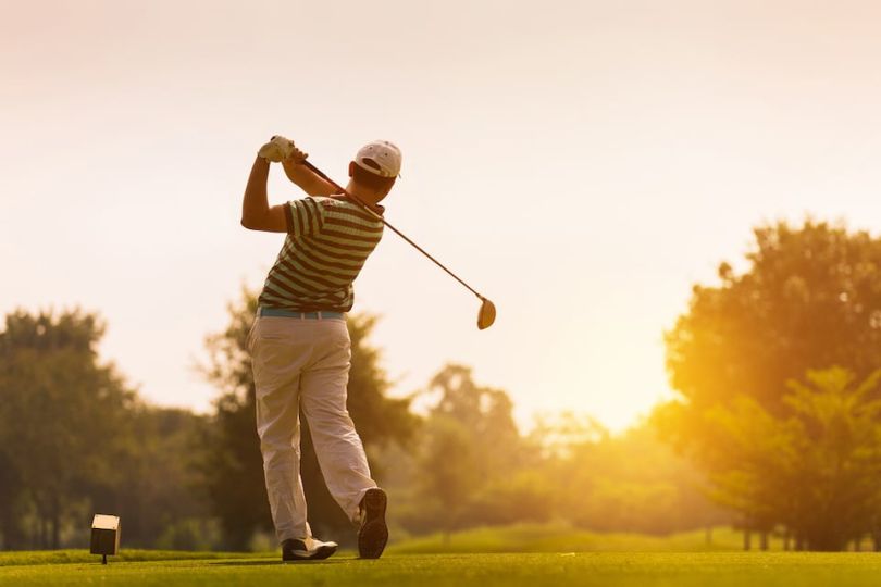 Man playing golf in the sunset
