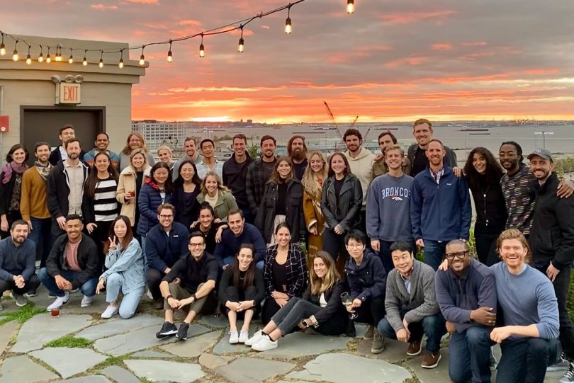 Ethic team photo outside at dusk with a body of water behind them