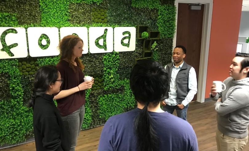 Fooda team chatting around company logo