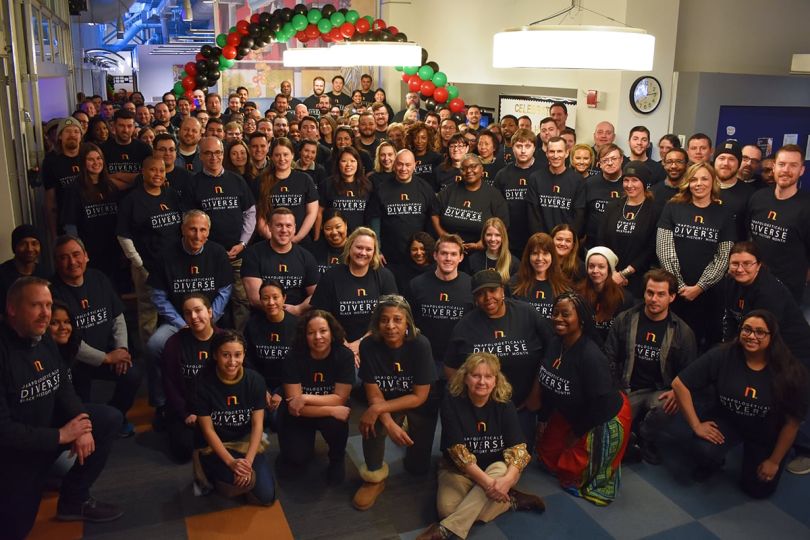 Group of people pose together in matching branded black tshirts