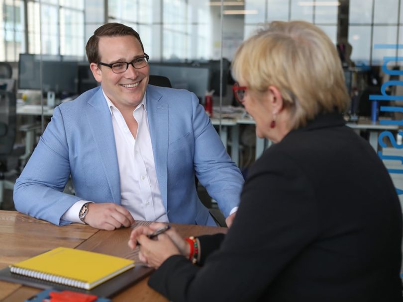 Tim Peck sits at a conference table with a woman.