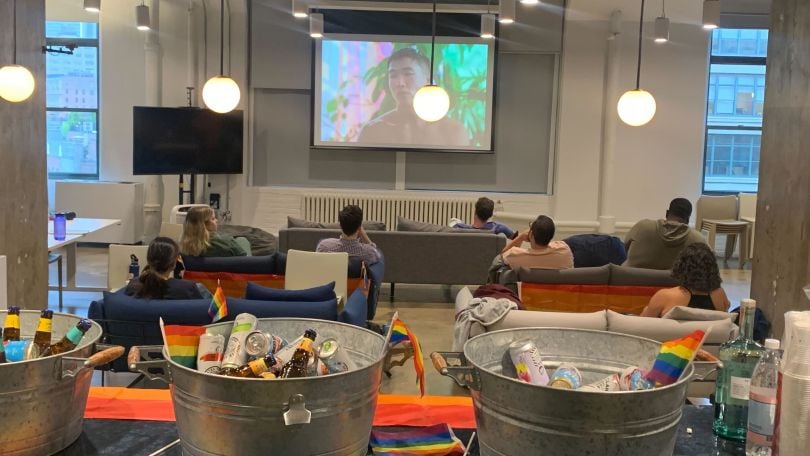 Harry’s team members watch a show in a casual communal space. 