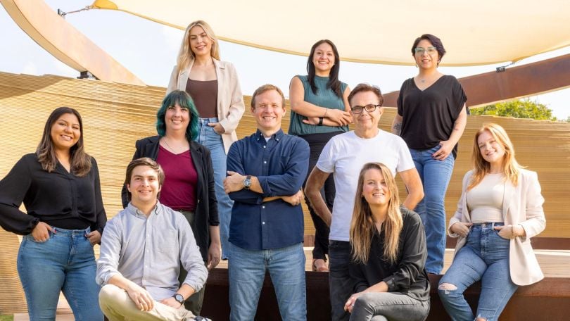 Invoice Home employees gather for a group photo outside in front of a tan structure.