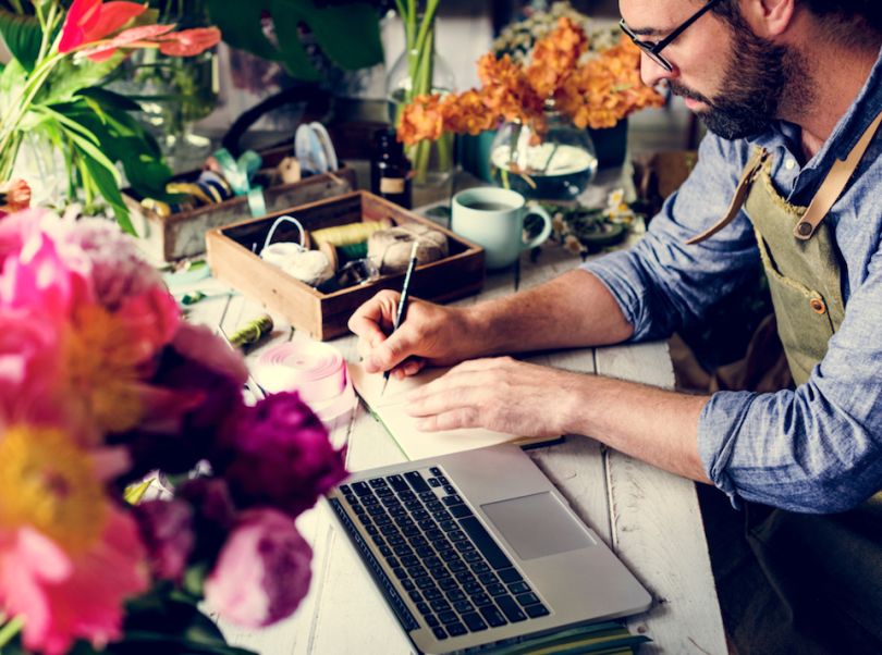 Male florist writing in notebook