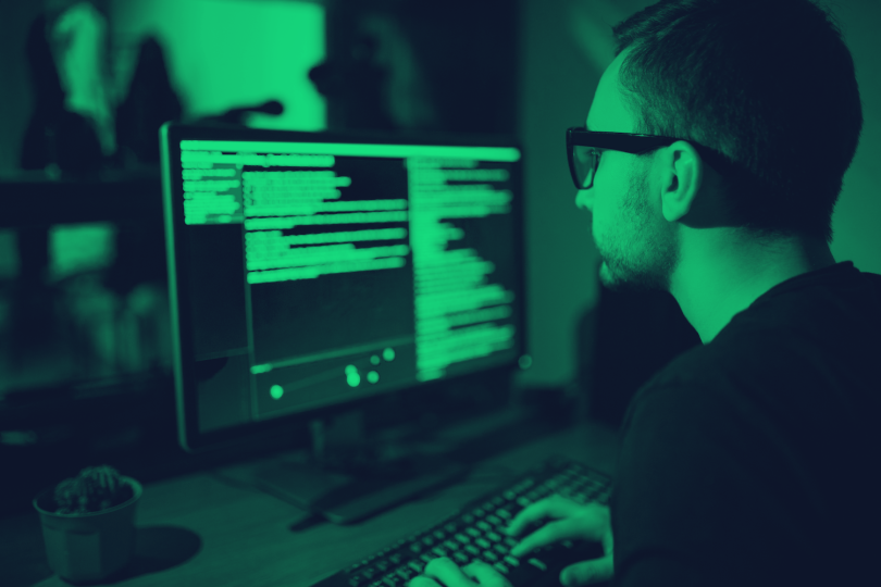 Hacker looking at computer monitors stock