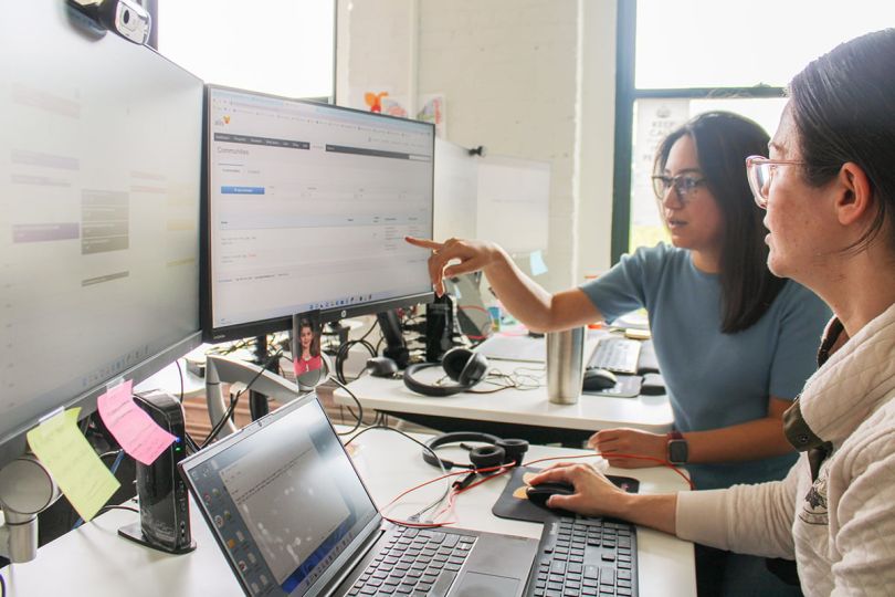 Two Medtelligent team members looking at a computer monitor working on a project together