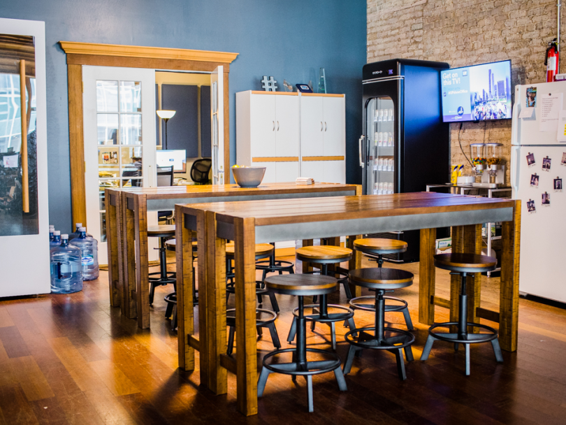 the fully stocked kitchen with wooden high-top tables in the UPshow office 
