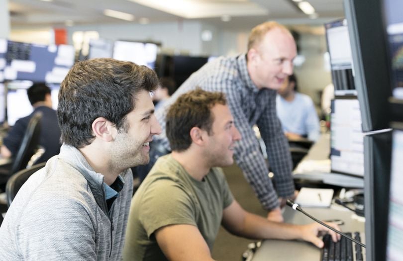 Optiver team members working around a computer