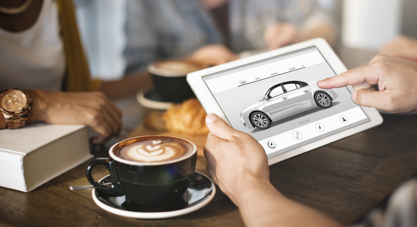 two hands holding a tablet and examining a car-buying interface.