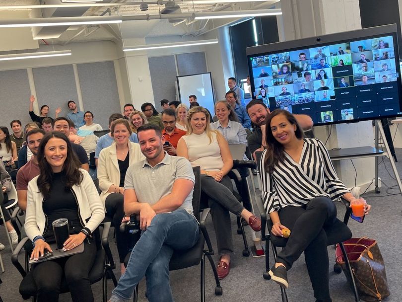 SIMON team members in a staff meeting in the office with some people on Zoom
