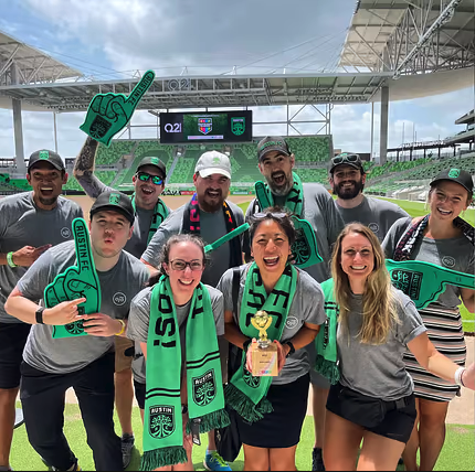 OJO Labs team on a sports field posing with green scarves