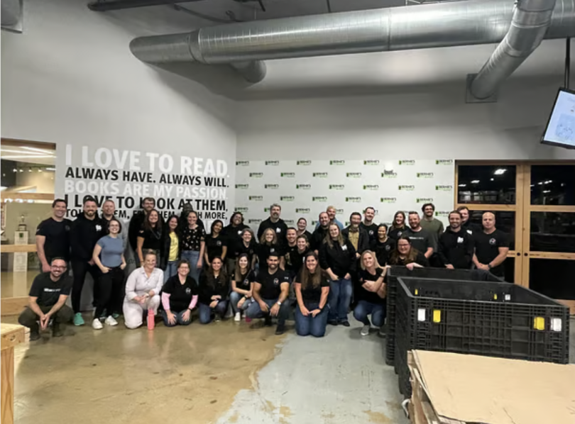 Gathering of employees, most wearing black shirts, lined up in three rows