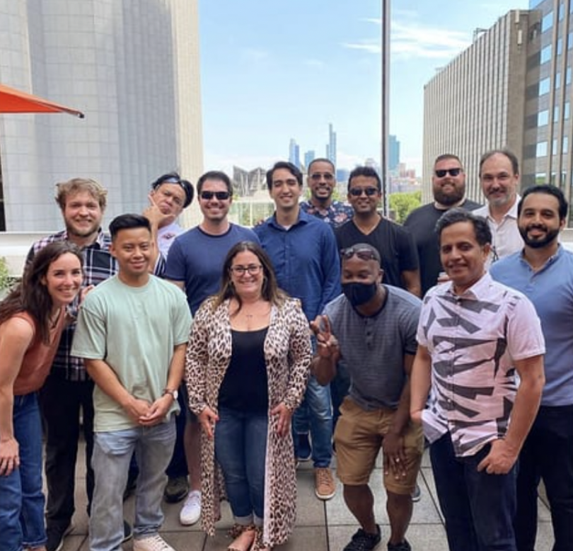 14 people standing outside in an urban setting of tall buildings