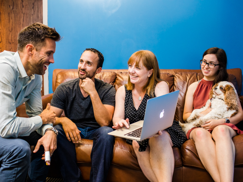 Tony's team and a King Charles spaniel smile at him as he pulls up a website
