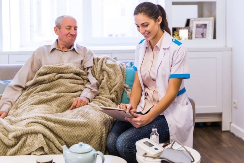 female nurse uses iPad to tend to nursing home patient
