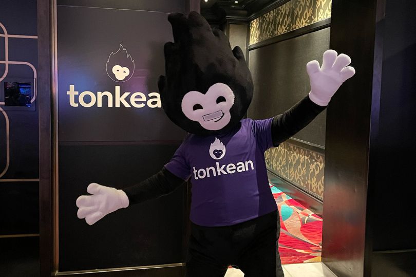 Tonkean mascot standing in front of company logo on the wall