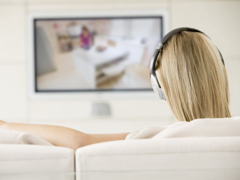 Woman wearing headphones while watching TV