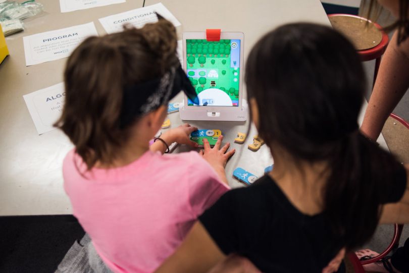 Two young girls playing a game on a tablet
