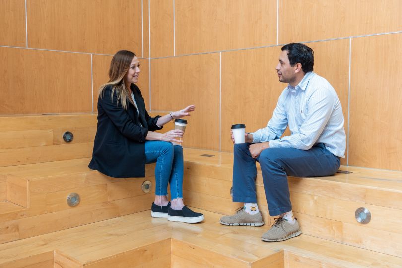 Ascension team members sit on natural-colored wood steps and chat
