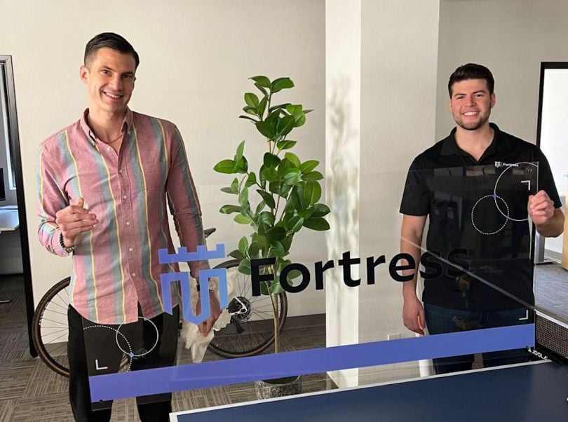 Members of the Fortress team pose with a glass display featuring the company's logo