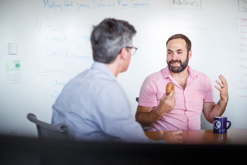 VelocityEHS team members sitting at a table, talking