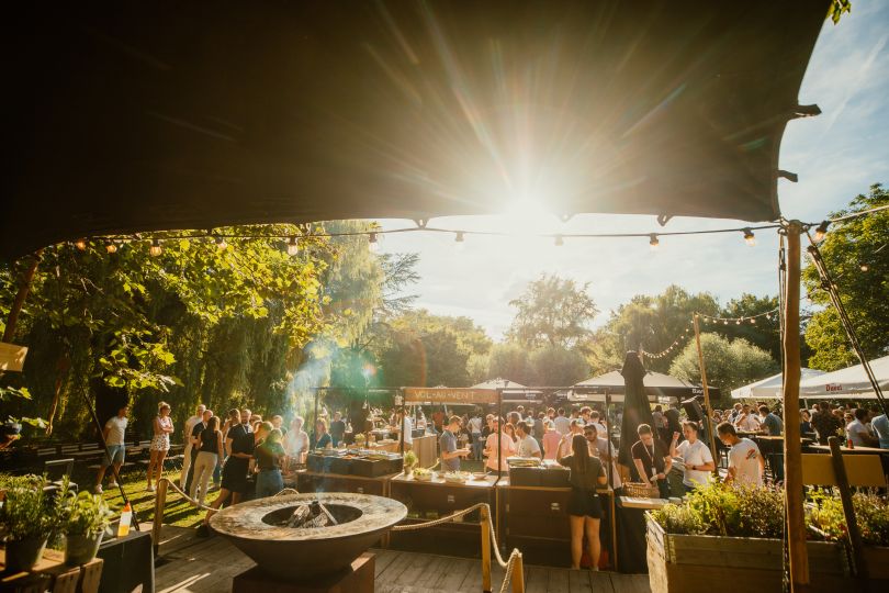 Photo of a Showpad event. People are outside on a patio with a firepit and there is a sunflare.