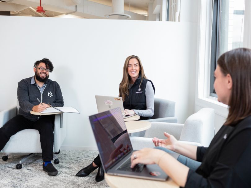 three employees collaborating, each in their own desk