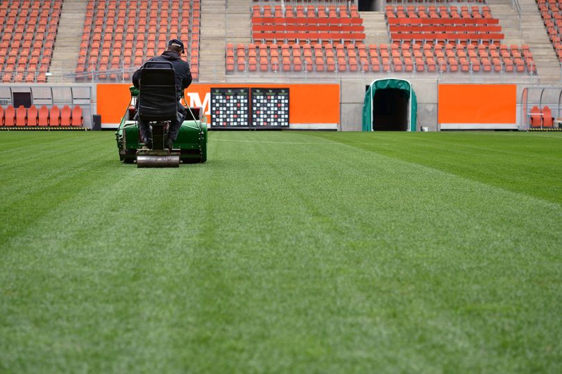 Man mowing the grass at a football stadium