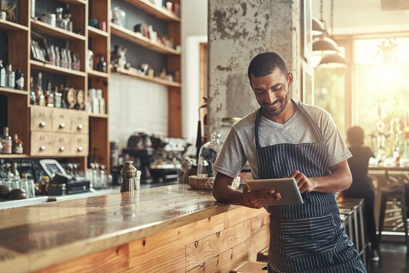 Male owner of cafe using digital tablet