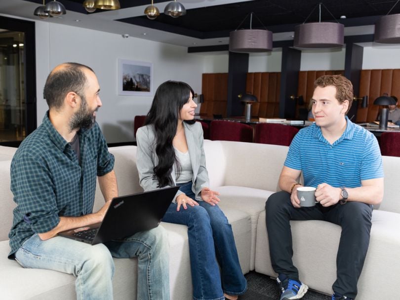 Muammer Akgün and two team members sitting down, talking.