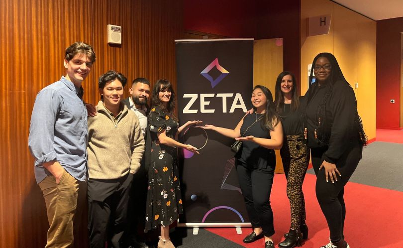 A group of Zeta employees with a Zeta banner